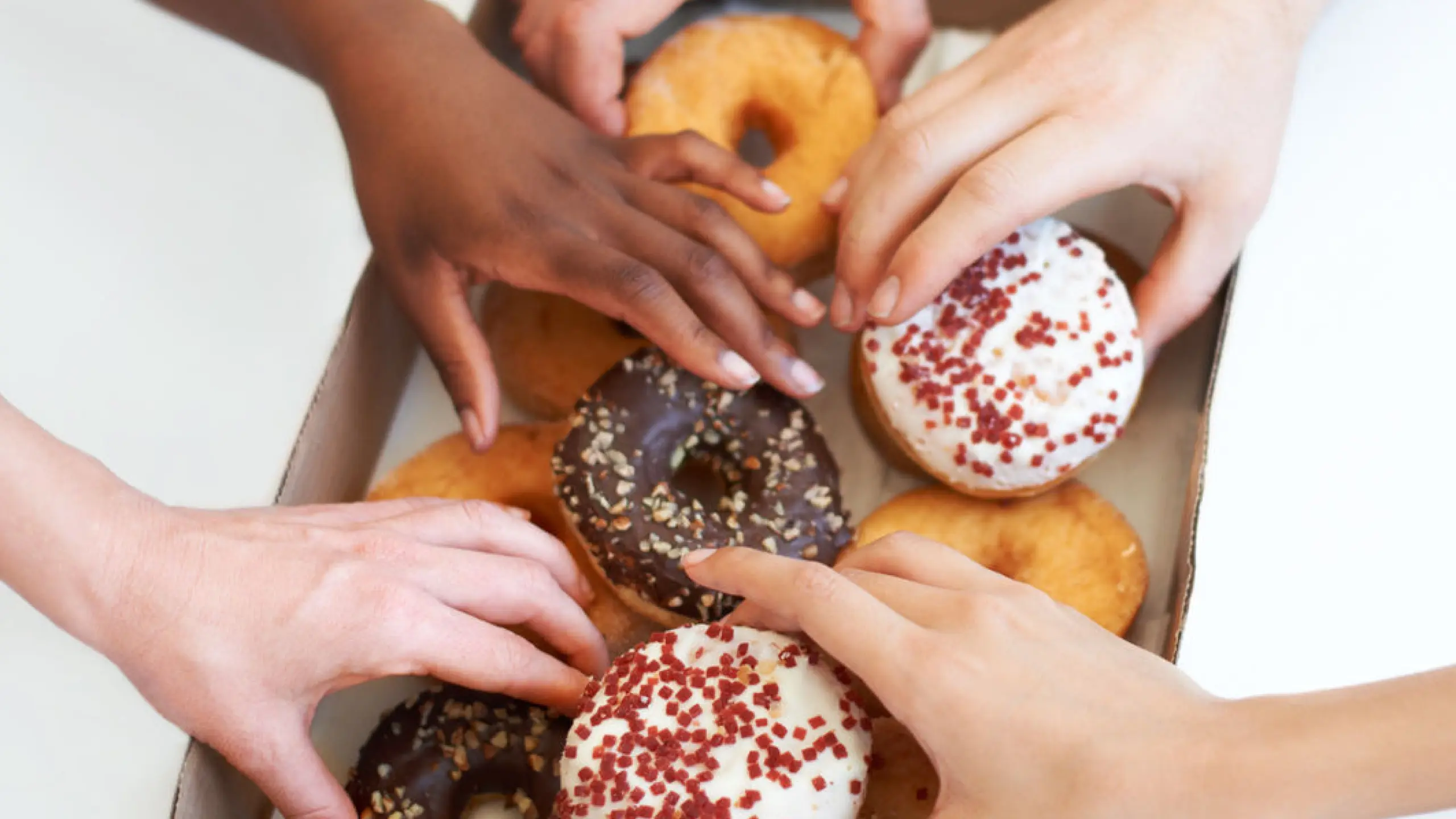 Frauenhände, die in eine Verpackung mit Donuts greifen