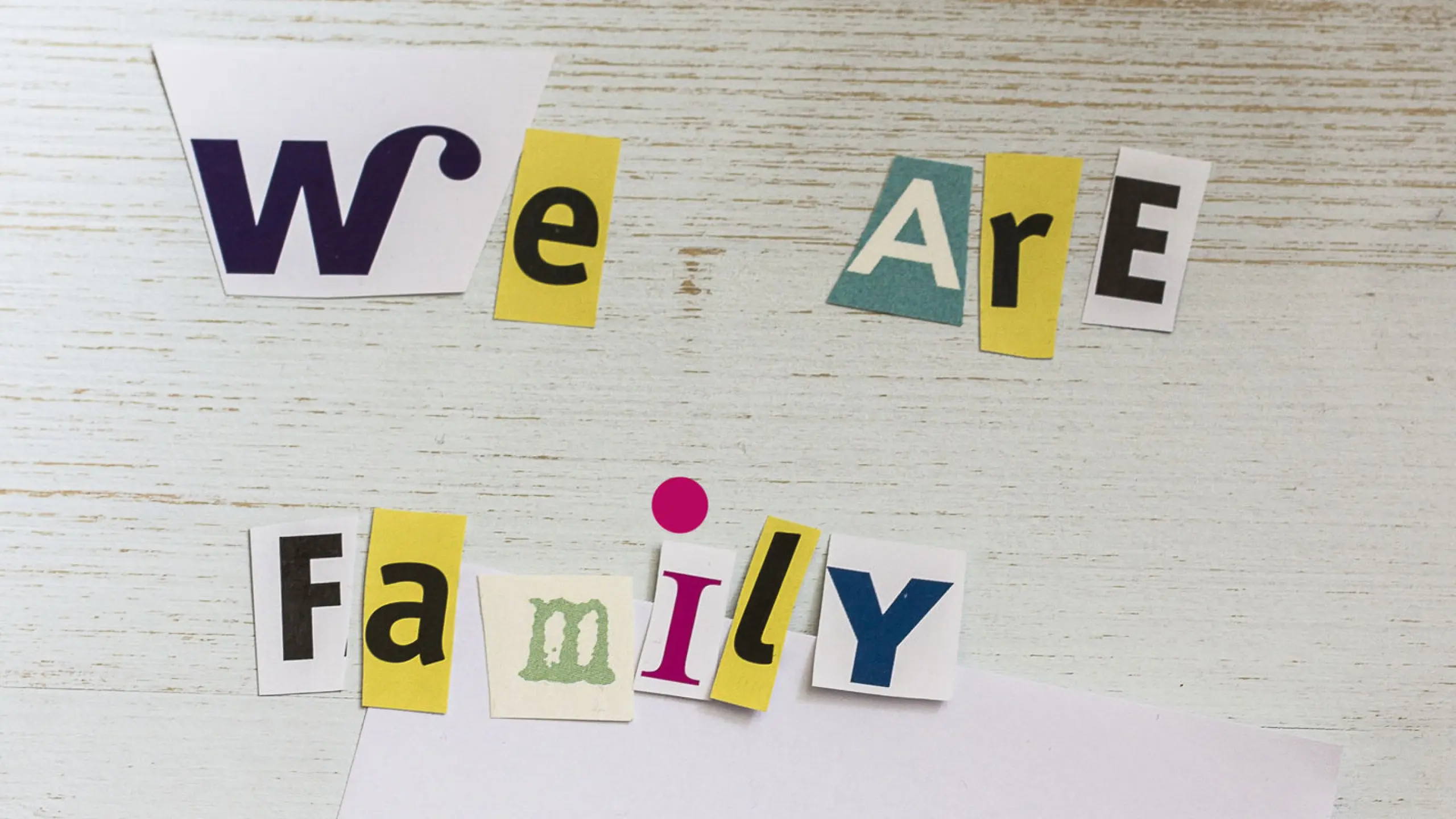 Schriftzug &quot;We are Family&quot; mit der Zeichnung eines Kindes, die Strichmännchen stellen eine Familie dar.