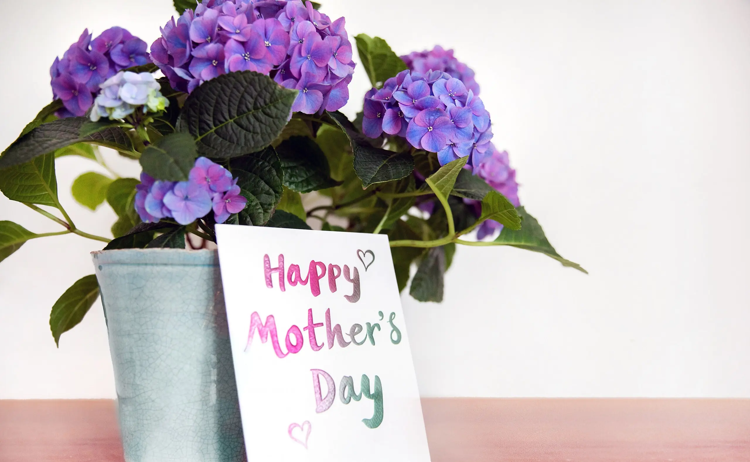 Muttertagskarte, die auf einem Tisch vor einem Blumenstrauß zu sehen ist